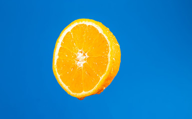 Przekrojona pomarancza.. Polowka owocu. Swieze cytrusy. Pomarancza na niebieskim tle.  Soczystey owoc.  Naruralne witaminy. Krople wody na skorce pomaranczy.