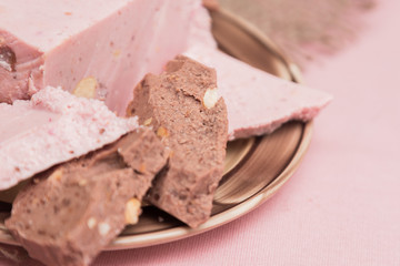 Tiles of a broken exquisite hand-made chocolate with dried and fresh berries, nuts.