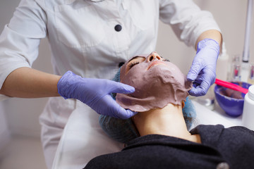 Obraz na płótnie Canvas The cosmetologist removes the mask from the face of the client in the beauty salon