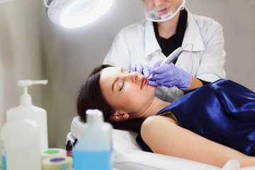 Young woman having permanent makeup on lips in beautician salon. Close up