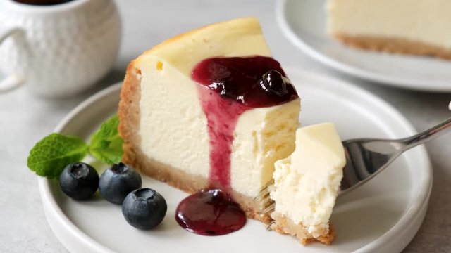 Cheesecake with blueberry sauce. Taking bite of delicious new york cheesecake with a fork. Eating cheesecake 4k footage