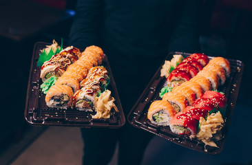 Close-up Hand Waiter holding Set Delicious fresh Sushi slate plate, Japanese raw fish   in traditional restaurant. Philadelphia flesh Rolls served on plate in sushi bar.  Japan food menu service