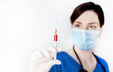 Girl doctor holds a syringe in her hand with a medicine against coronavirus on a white background with copy space for your text