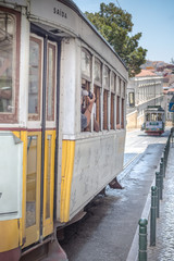 Naklejka na ściany i meble yellow tram driving downhill with tourists in lisbon