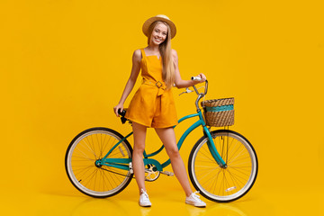 Fototapeta na wymiar Pretty young girl in summer clothes posing with stylish vintage bicycle
