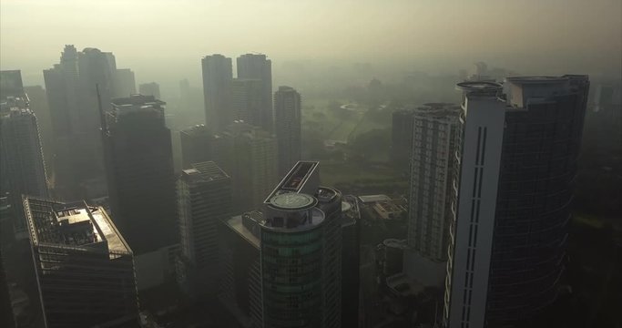 Straight aerial flight over high rise buildings approaching park. Drone, 4K.