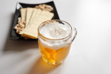 Fototapeta na wymiar Mug of unfiltered light wheat beer with beer snacks on white table