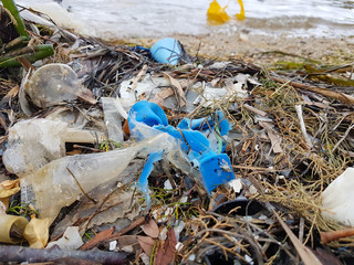 Plastic waste littered by high tide line in harbour of Spanish port.