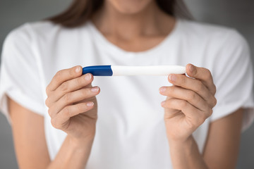 Close up view caucasian young female hands holding pregnancy or ovulation plastic test, waiting for positive or negative result, pregnancy confirmation or denial accurate easy convenient tool concept