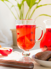 A glass of homemade cranberry juice, a jug of drink, fruits and cookies on the windowsill in the morning - light breakfast
