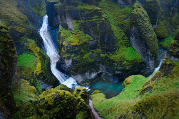Iceland waterfall. The picturesque canyon Fjadrargljufur, green cliffs and blue water of the river