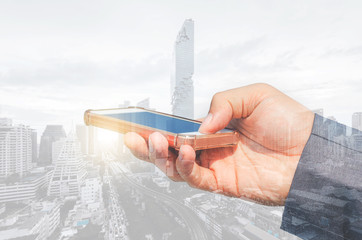 double exposure city and businessman using smartphone searching with internet online networking. device mock up mobile phone texting communication connecting.