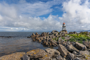 Fototapeta na wymiar White lighthouse with red roof in Norway. Norwegian scenic landscape with a tall white lighthouse. Lighthouse on the background of harsh Scandinavian nature. Norway.