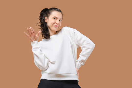 Sportive and playful girl in white pullover and black leggings grimace in studio