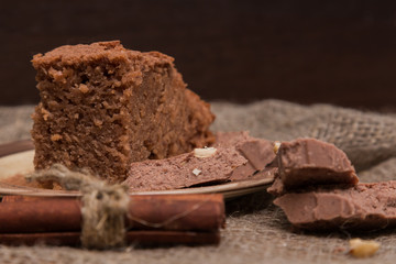 Fresh brownies decorated with orange peel on wooden board, space for text. Delicious chocolate pie.