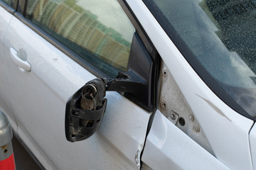 Torn car mirror hanging on wires, consequences of a car accident. Collision of transport, details close-up