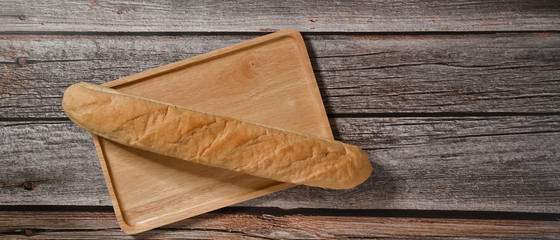 Freshly baked baguette isolated on wooden table. Top view