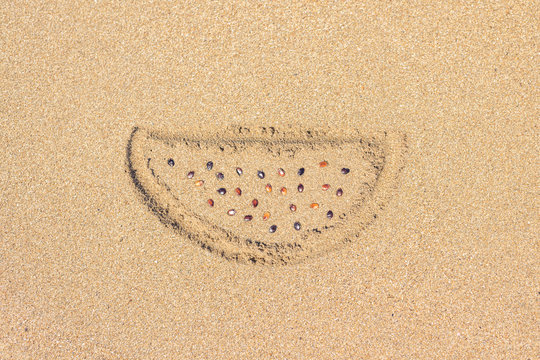 Creative. A piece of watermelon painted on the wet sand of a beach with real bones. Concept. Summer, travel