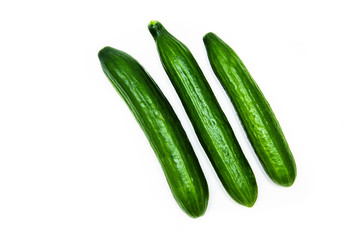 Three greenhouse green, smooth cucumbers on a white background nearby. Greenhouse cucumbers from above and in front. Cucumbers in macro, butt, tails of  cucumbers