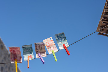 Fototapeta na wymiar Money of south-east Asia with a clothespin on a rope opposite blue sky. Сhina yuan (CNY) Currency, Hong Kong, Indonesia, Malaysia, Thai, Singapore dollar. Travel, tourism, insurance. concept