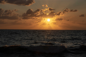 Tramonto rosso sul mar tirreno tra nuvole rosse lievi raggi di sole