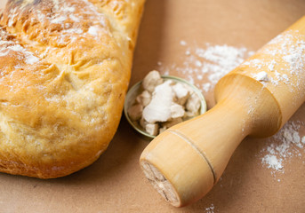 Pan casero y un rodillo rociado con harina sobre una mesa de madera.