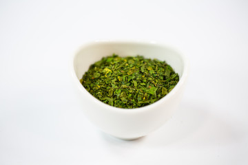 Parsley dried in a bowl, white background