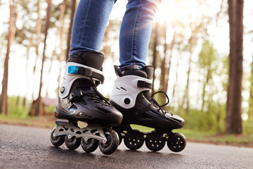 Close up picture of rollerblades, unknown person wearing rollerskates to spend time actively, black...