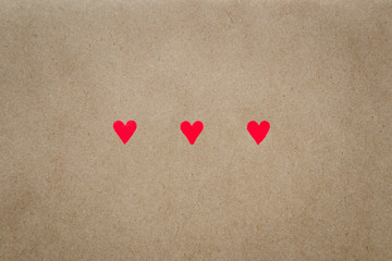Fototapeta premium Image of three hearts on beige background of craft paper with copy space