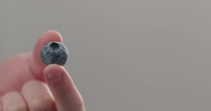 Slow motion man hand show ripe blueberry closeup