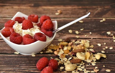 muesli with yogurt, berries and nuts on a wooden table