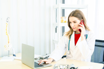 Female beautiful wearing a doctor uniform using a notebook computer and talking case of treatment.