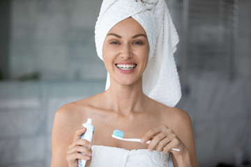 Beautiful fresh woman without make-up pose in bathroom after shower, holding toothpaste and...