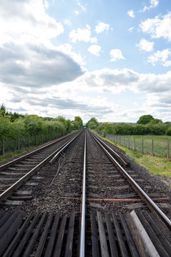 Quiet double track train line running in a straight line in the countryside.