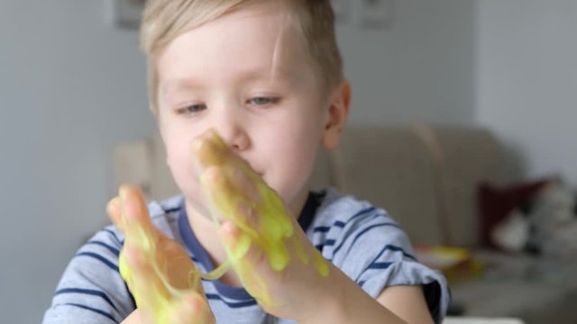 Cute kid boy playing with light green slime. Close up