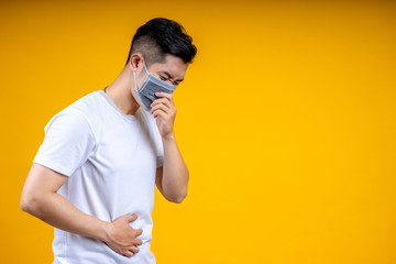 Asian man is wearing a white t-shirt and wearing a mask, holding an alcohol spray bottle. He was spraying it for cleaning  or washing his hands to prevent an outbreak of coronavirus or covid-19.