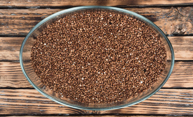 Buckwheat in a glass bowl. Raw buckwheat porridge.