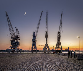A row of 4 old harbor cranes in the city of Antwerp.
