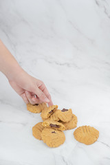 The hand is taking fresh homemade chocolate cookies and space for text on marble background