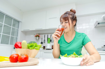 pretty asian woman slim body in green shirt dieting and drinking homemade detox juice with fresh vegetable salad sitting in at house, lifestyle, good healthy, diet food, fruit juice and drink concept