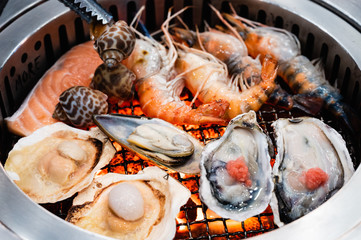 Salmon, oyster, river prawn, scallop, mussel and babylonia areolata on a grill stove