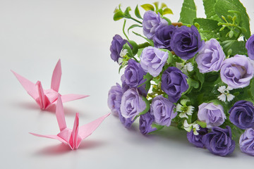 Pink origami crane and purple flowers, shallow depth of field