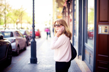 Confident woman talking with somebody on her smartphone while walking on the street