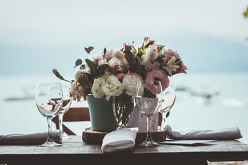 wedding flower bouquet placed on the table with glasses on side and the beach on the background