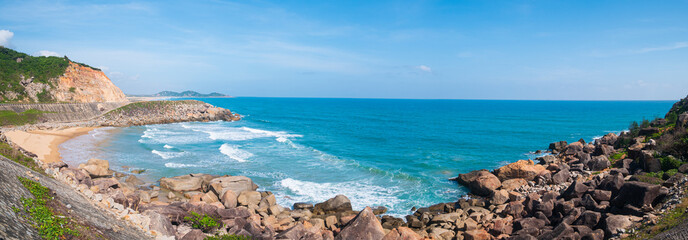 Expansive view of scenic tropical bay, lush green woodland and blue waving sea. The easternmost coast in Vietnam, Phu Yen province between Da Nang and Nha Trang.