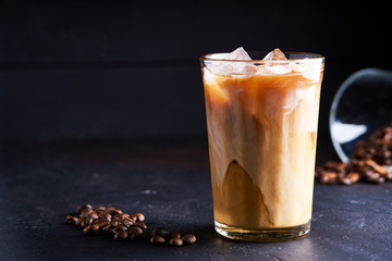 Tasty ice coffee with milk , cold drink in glass on dark background Copy space