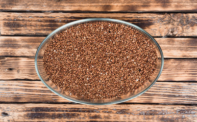 Buckwheat in a glass bowl. Raw buckwheat porridge.