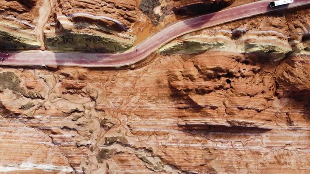 Top View of Rainbow Mountains Geological Park. Stripy Zhangye Danxia Landform Geological Park in Gansu Province, China. Flying Drone Picture of Tourist Buses on a Road in a Valley on Sunny Day.