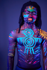 colorful fluorescent body art with ethnic prints, young male posing at camera. luminescence, fluorescence, body art, fashion model