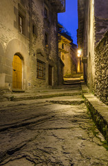 Fototapeta premium Callejuela del pueblo medieval de Rupit iluminado al anochecer (Cataluña, España).